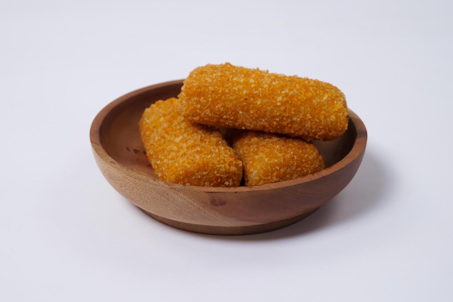 American Risoles or risoles mayo is a traditional Indonesian snack filled with smoked beef or sausage, boiled eggs and mayonnaise. Crispy texture on the outside. Risoles on wood plate isolated white. photo