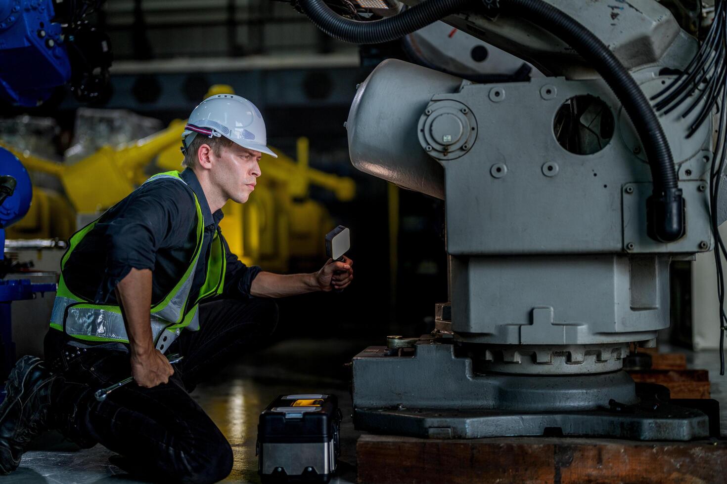 male engineer workers maintenance automatic robotic arm machine in a factory. worker checking and repairing automatic robot hand machine. photo