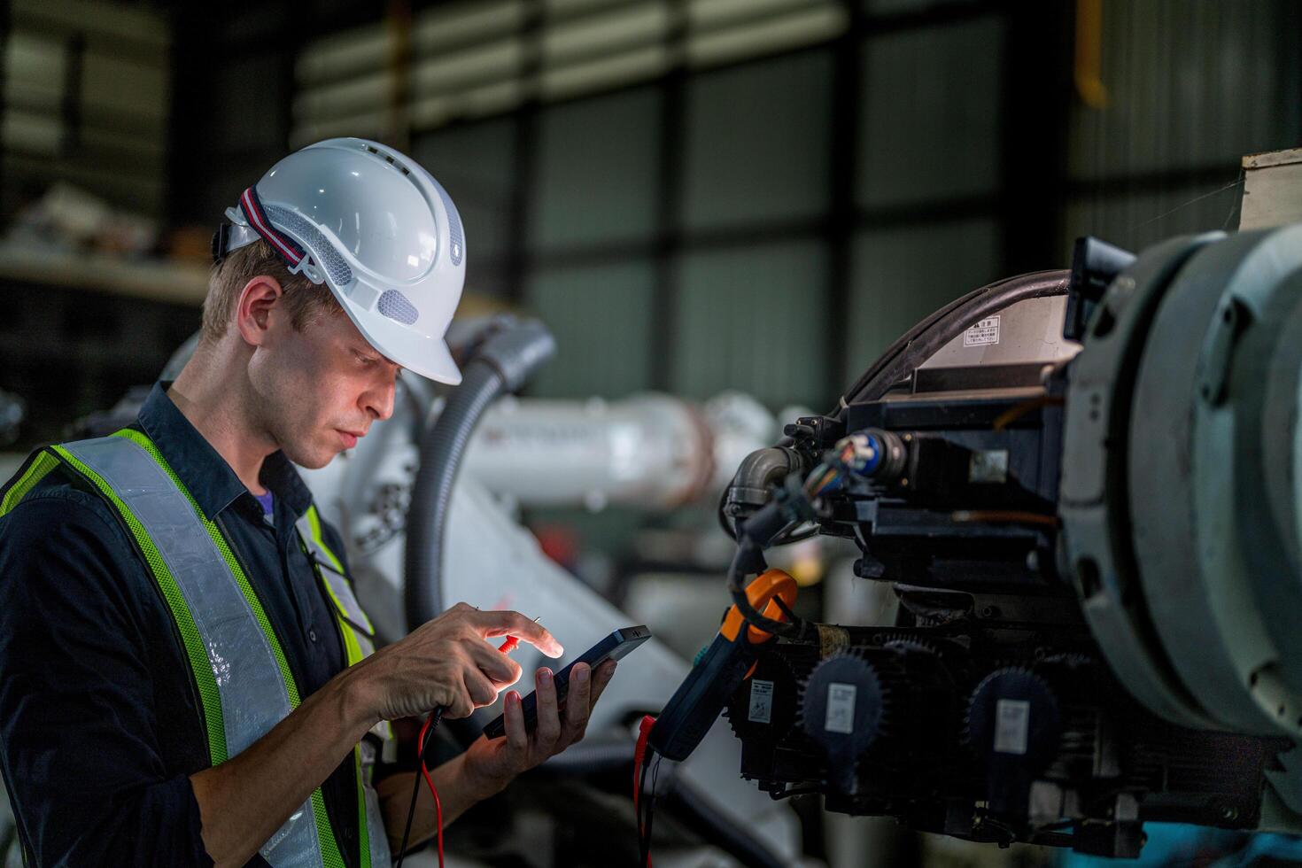 male engineer workers maintenance automatic robotic arm machine in a factory. worker checking and repairing automatic robot hand machine. photo