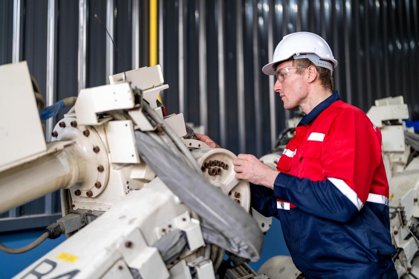 male engineer workers maintenance automatic robotic arm machine in a factory. worker checking and repairing automatic robot hand machine. photo