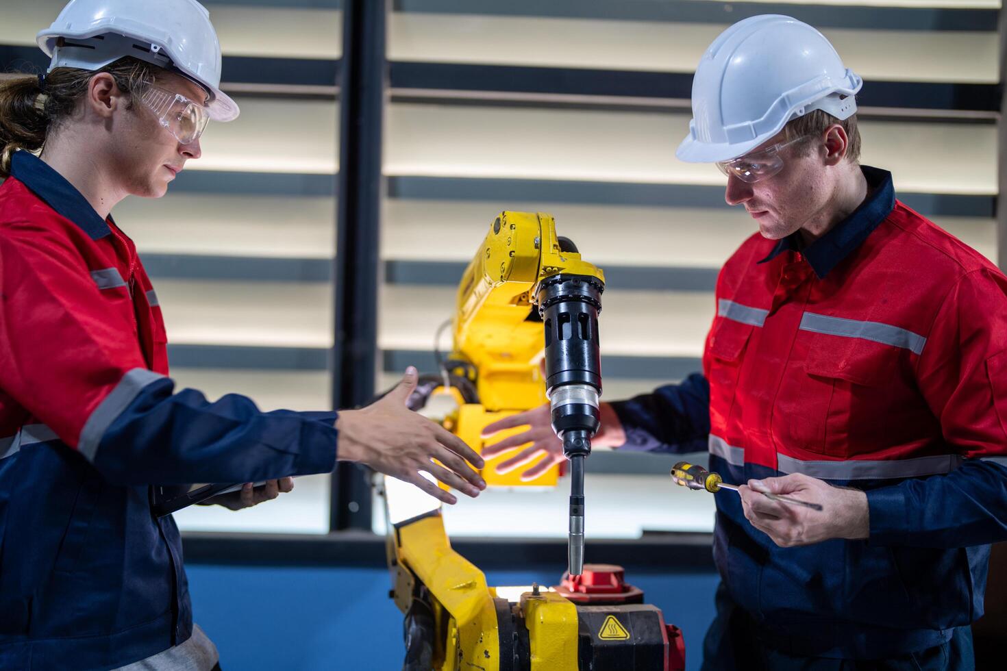 male engineer workers maintenance automatic robotic arm machine in a factory. worker checking and repairing automatic robot hand machine. photo