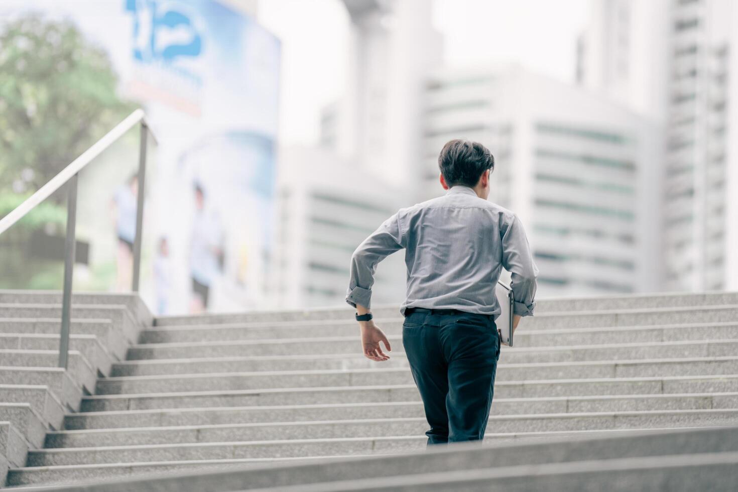 Asian businessman walking to work diligently and briskly in the morning in a big city. A man in a business suit, dressed in a smart suit, runs to work during rush hour in corridors and stairs. photo