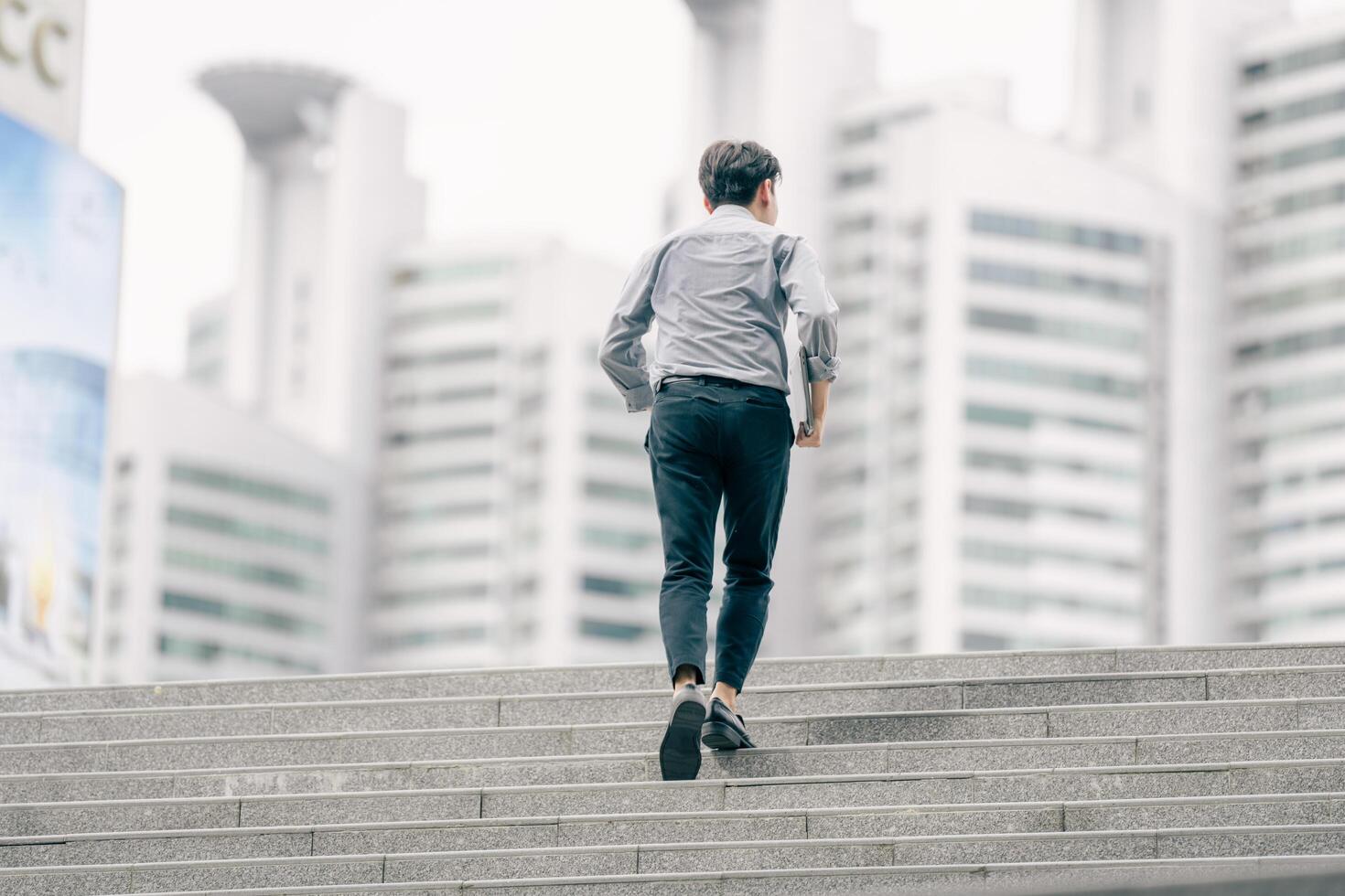 Asian businessman walking to work diligently and briskly in the morning in a big city. A man in a business suit, dressed in a smart suit, runs to work during rush hour in corridors and stairs. photo