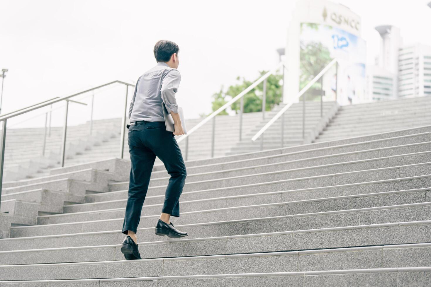 Asian businessman walking to work diligently and briskly in the morning in a big city. A man in a business suit, dressed in a smart suit, runs to work during rush hour in corridors and stairs. photo
