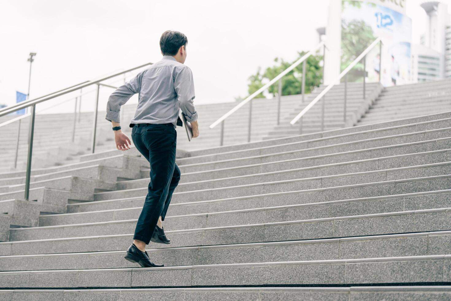 Asian businessman walking to work diligently and briskly in the morning in a big city. A man in a business suit, dressed in a smart suit, runs to work during rush hour in corridors and stairs. photo