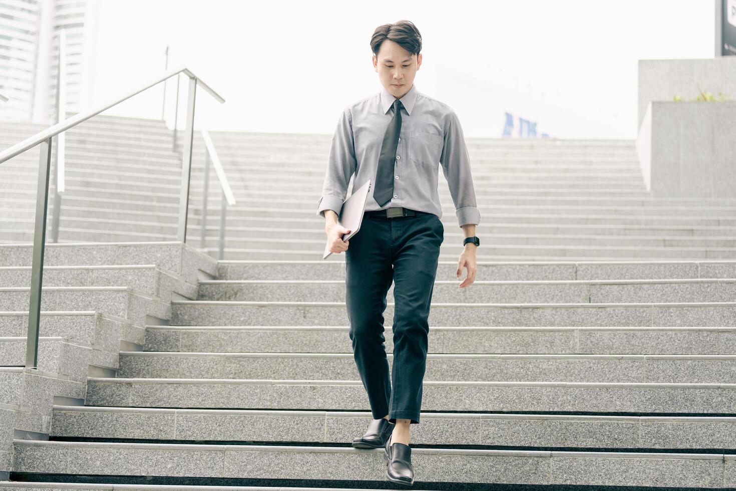 Asian businessman walking to work diligently and briskly in the morning in a big city. A man in a business suit, dressed in a smart suit, runs to work during rush hour in corridors and stairs. photo