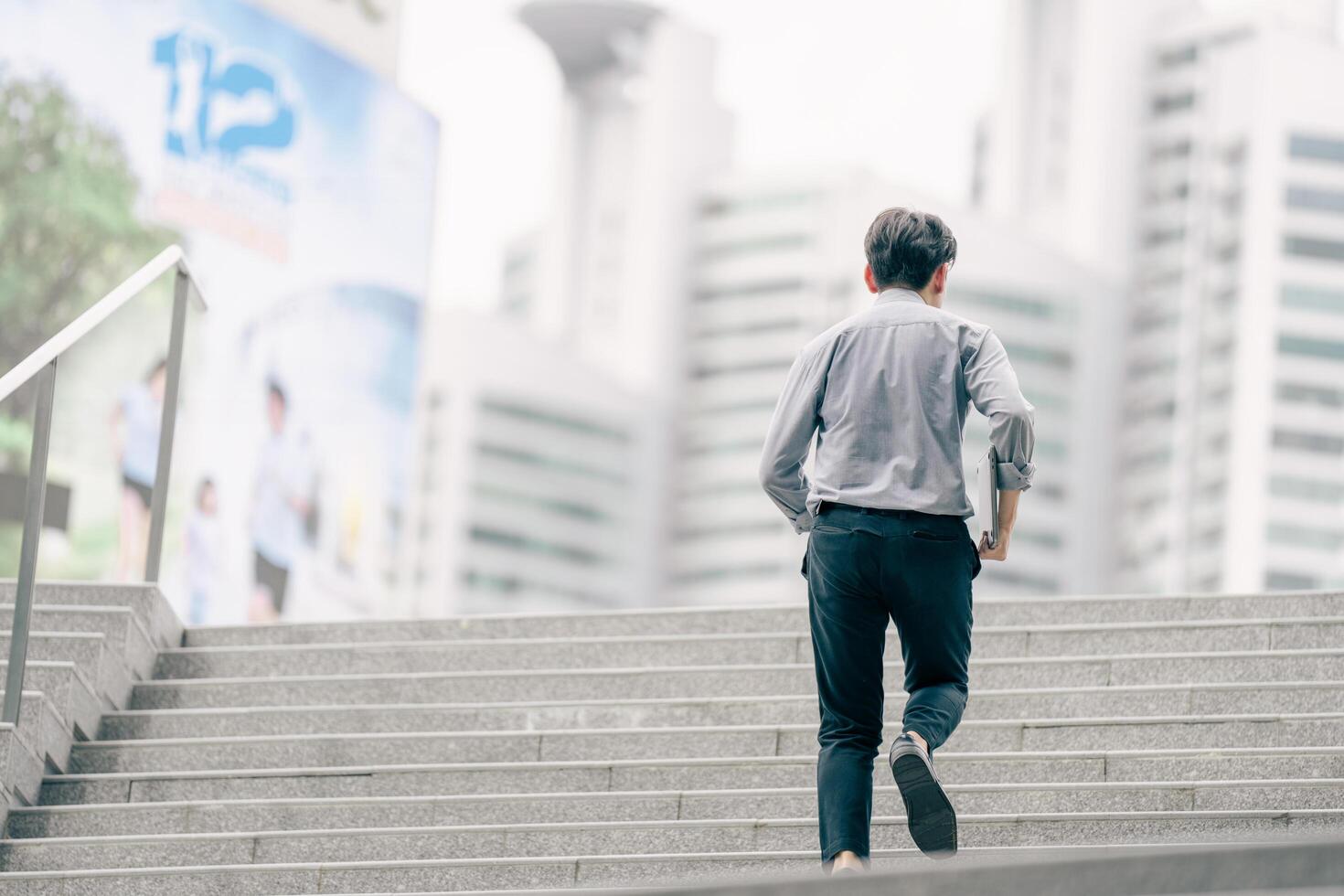Asian businessman walking to work diligently and briskly in the morning in a big city. A man in a business suit, dressed in a smart suit, runs to work during rush hour in corridors and stairs. photo