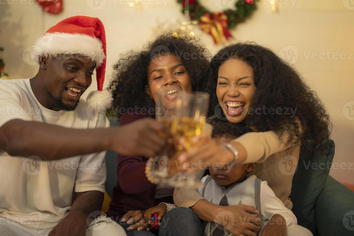 A lively Christmas celebration with three african friends enjoying drinks and holiday cheer on a sofa. The festive atmosphere includes Christmas trees, wreaths, lights, and decorations. photo