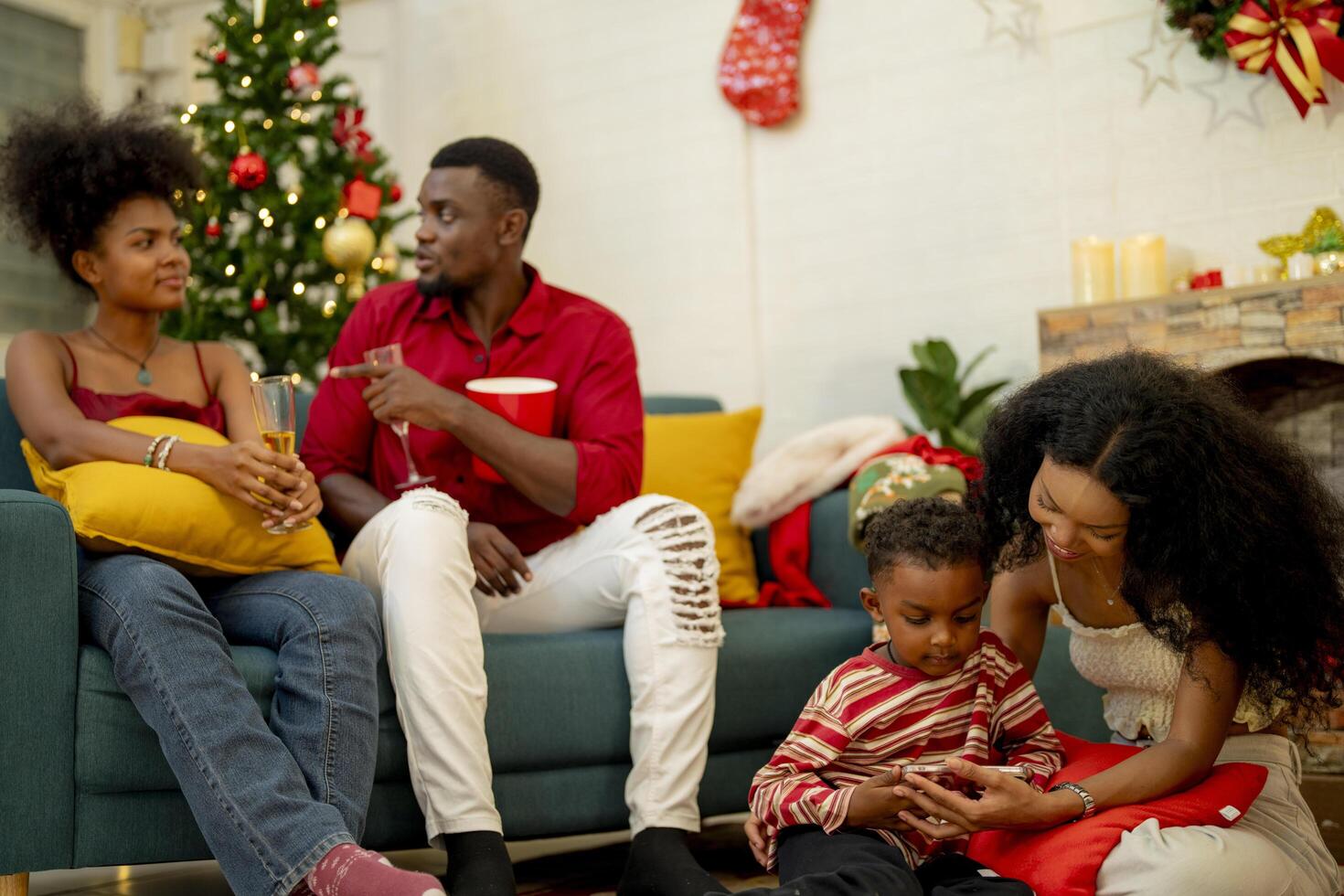 A family enjoying a cozy Christmas evening at home. The group gathers around the Christmas tree, sharing laughs and stories. The warmth of the festive season is felt as they relax and bond together. photo