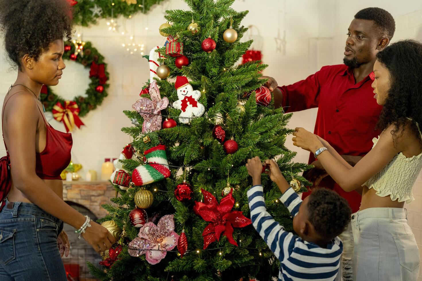 A family joyfully decorates a Christmas tree, hanging ornaments and festive decorations.The family members are engaged in adding the final touches to their beautiful Christmas tree. photo