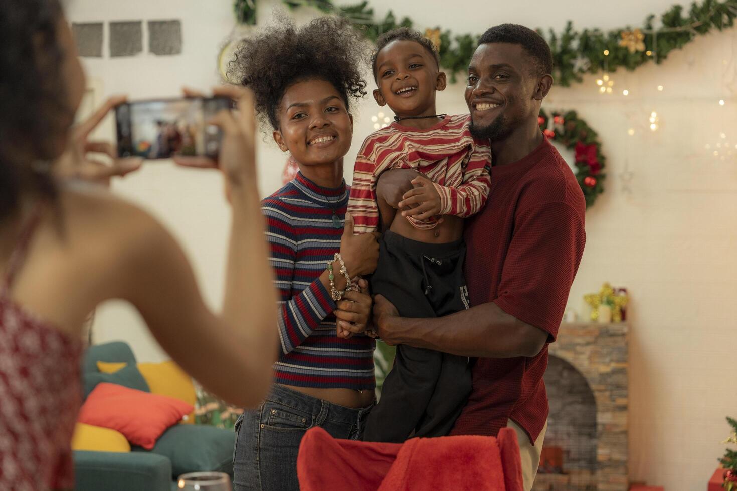 A joyful family gathers around the dinner table celebrating Christmas. The father, dressed in a Santa hat, gives a gift to the child, while everyone smiles with warmth and festive decorations. photo