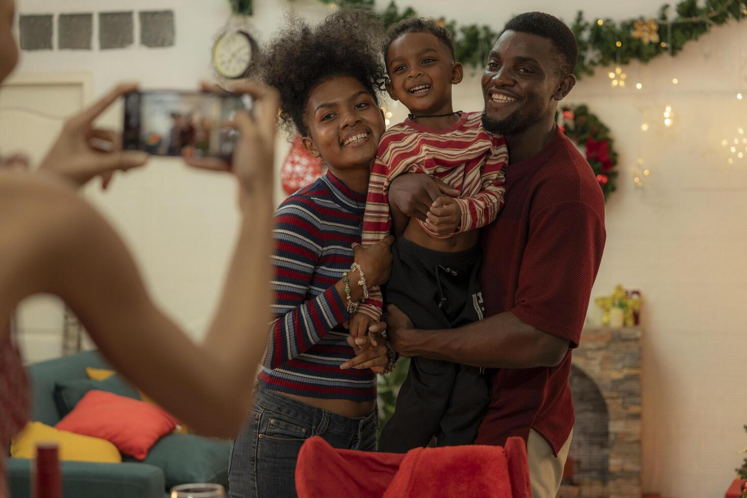A joyful family gathers around the dinner table celebrating Christmas. The father, dressed in a Santa hat, gives a gift to the child, while everyone smiles with warmth and festive decorations. photo