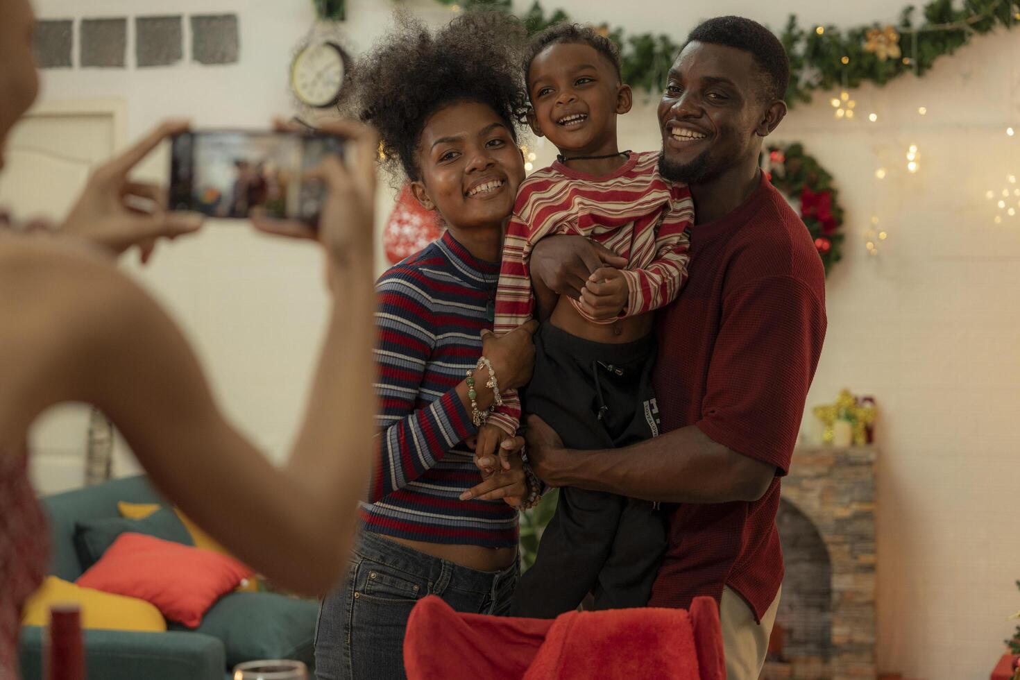 A joyful family gathers around the dinner table celebrating Christmas. The father, dressed in a Santa hat, gives a gift to the child, while everyone smiles with warmth and festive decorations. photo