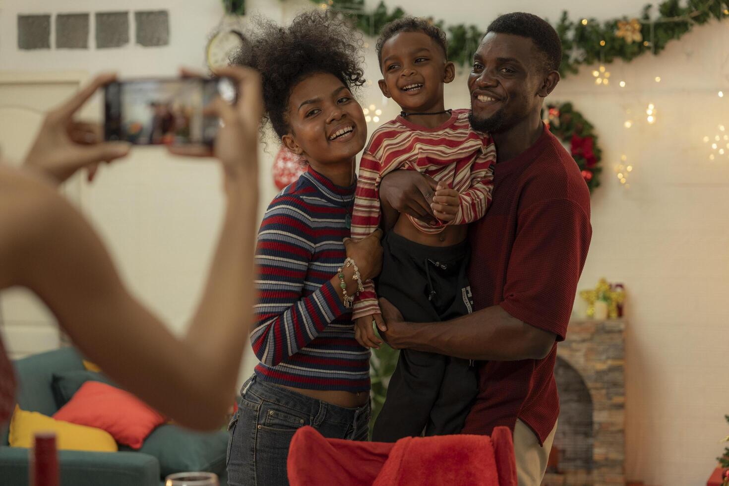 A joyful family gathers around the dinner table celebrating Christmas. The father, dressed in a Santa hat, gives a gift to the child, while everyone smiles with warmth and festive decorations. photo