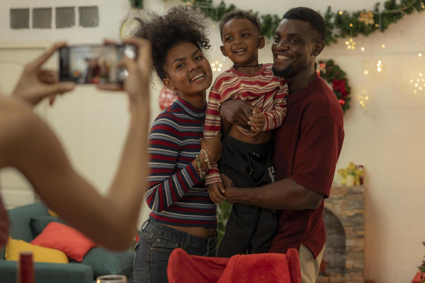 A joyful family gathers around the dinner table celebrating Christmas. The father, dressed in a Santa hat, gives a gift to the child, while everyone smiles with warmth and festive decorations. photo
