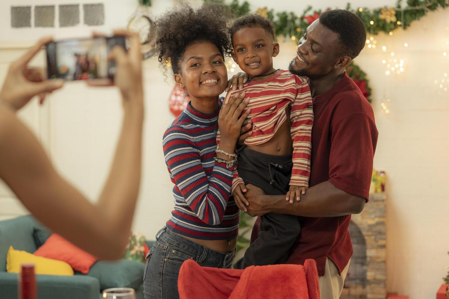 A joyful family gathers around the dinner table celebrating Christmas. The father, dressed in a Santa hat, gives a gift to the child, while everyone smiles with warmth and festive decorations. photo