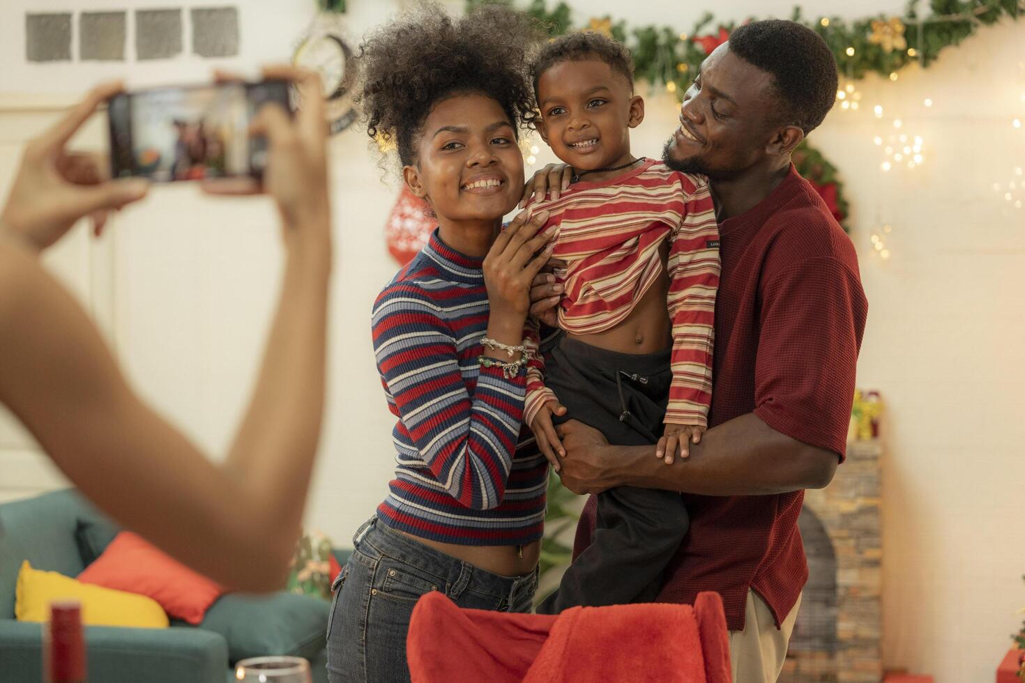 A joyful family gathers around the dinner table celebrating Christmas. The father, dressed in a Santa hat, gives a gift to the child, while everyone smiles with warmth and festive decorations. photo