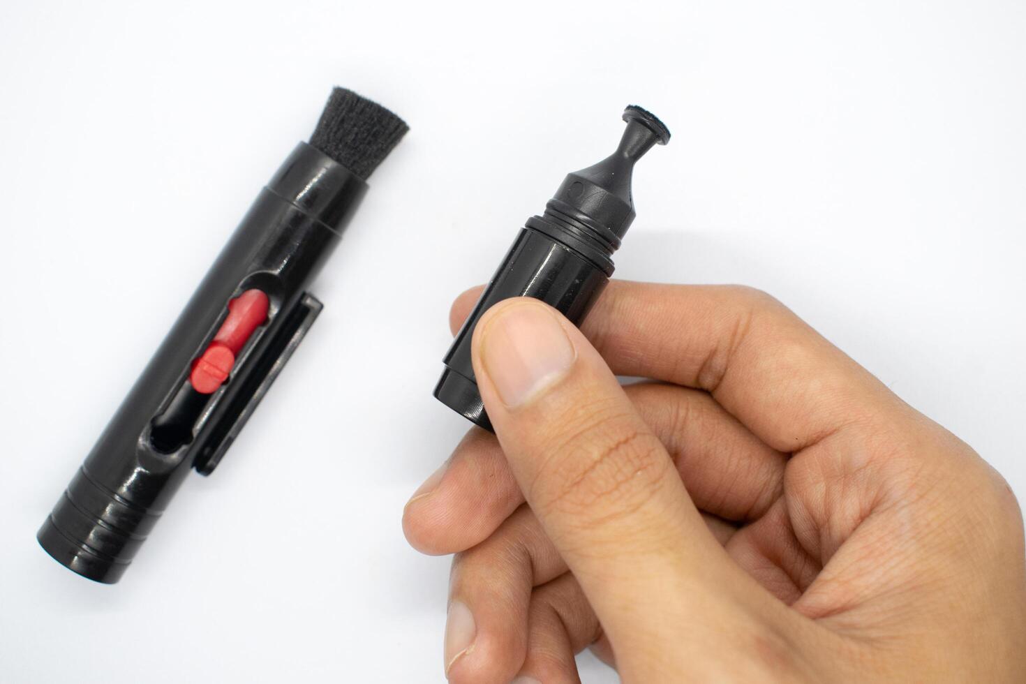 holding a lens pencil in his hand, A special brush for cleaning camera lenses on a white background photo
