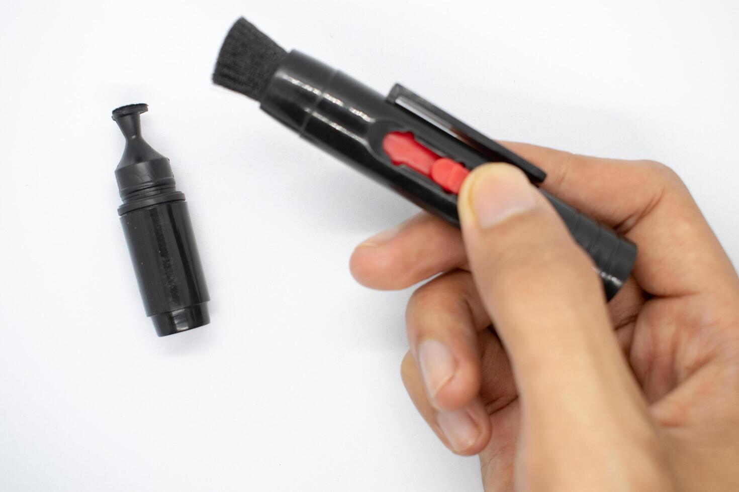 holding a lens pencil in his hand, A special brush for cleaning camera lenses on a white background photo