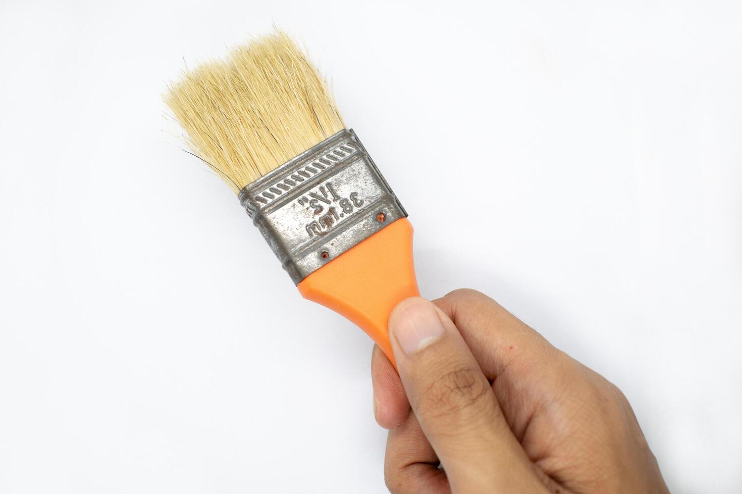 the hand is holding a wooden handle painting brush on a white background photo