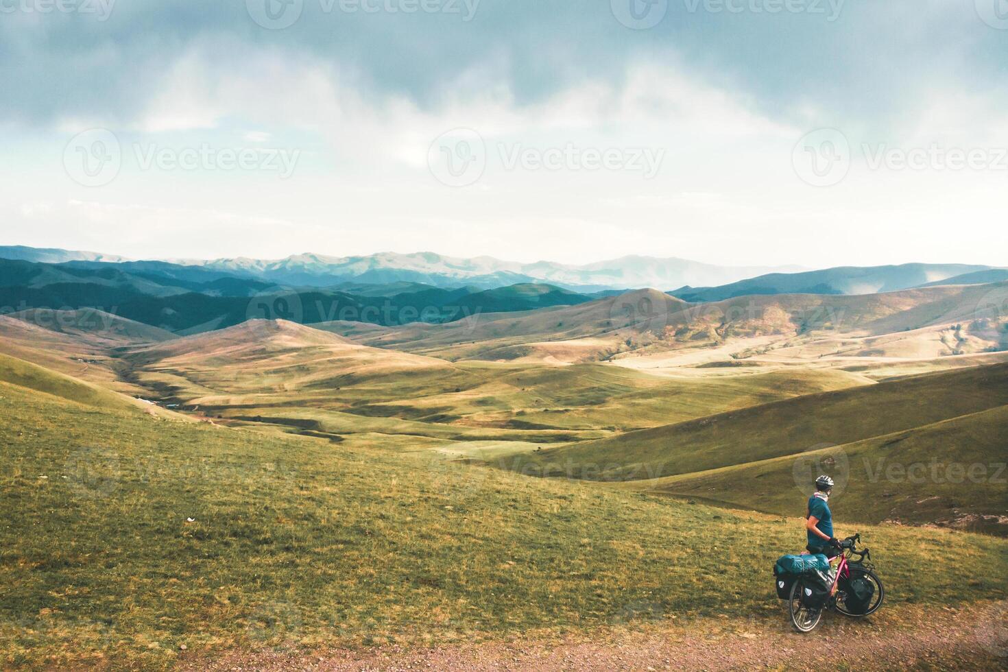 Male cyclist stand by bicycle right corner in caucasus countryside road. Safety and maintenance while cycling outdoors. Travel around Armenia by bicycle rocky terrain solo outdoors photo