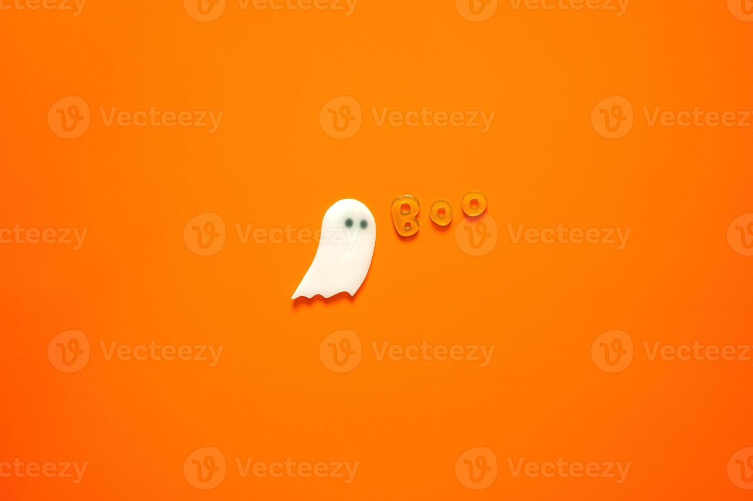Halloween background with gel stickers of white ghost sheet and alphabets on orange background. Minimal concept. photo