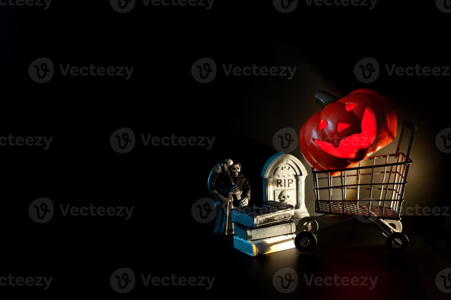 Halloween background with Jack o lantern that have light inside on shopping cart with small decorations on black background. Minimal concept. photo