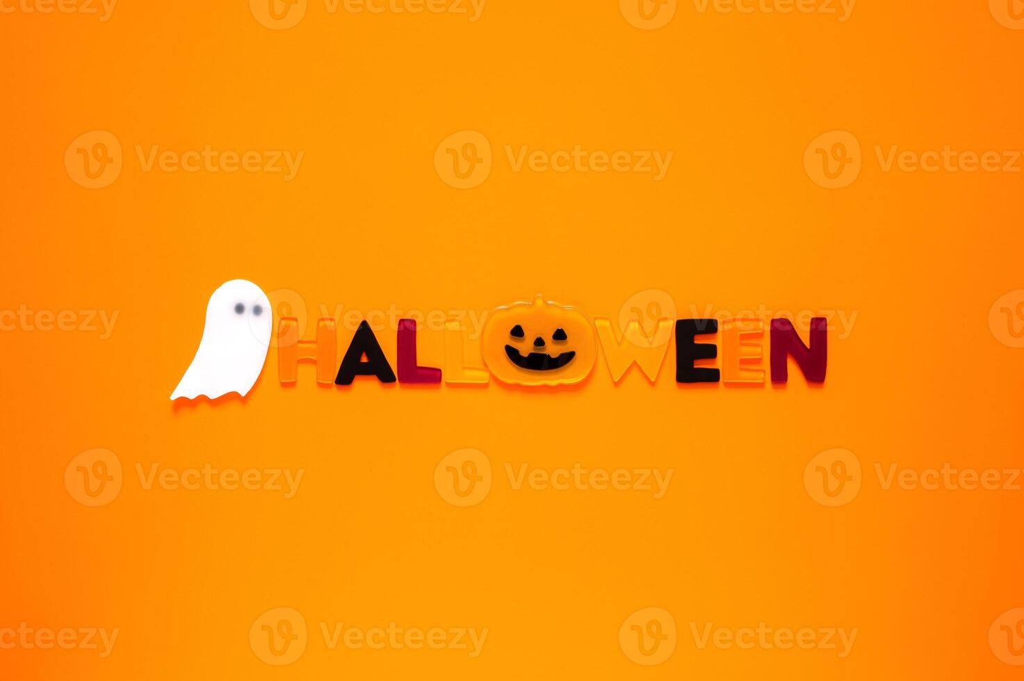 Halloween background with gel stickers of white ghost sheet and alphabets on orange background. Minimal concept. photo