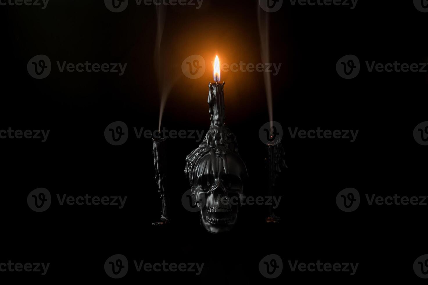 Halloween background with skull that have light candle on it with another candles that have smoke on black background. Minimal concept. photo