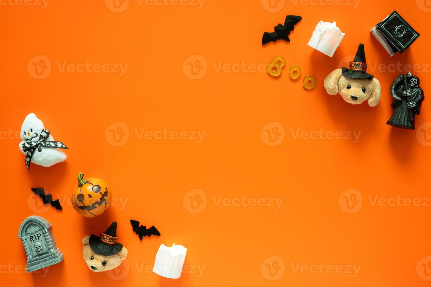 Halloween background with cute dolls and small decorations on orange background. Minimal concept. photo