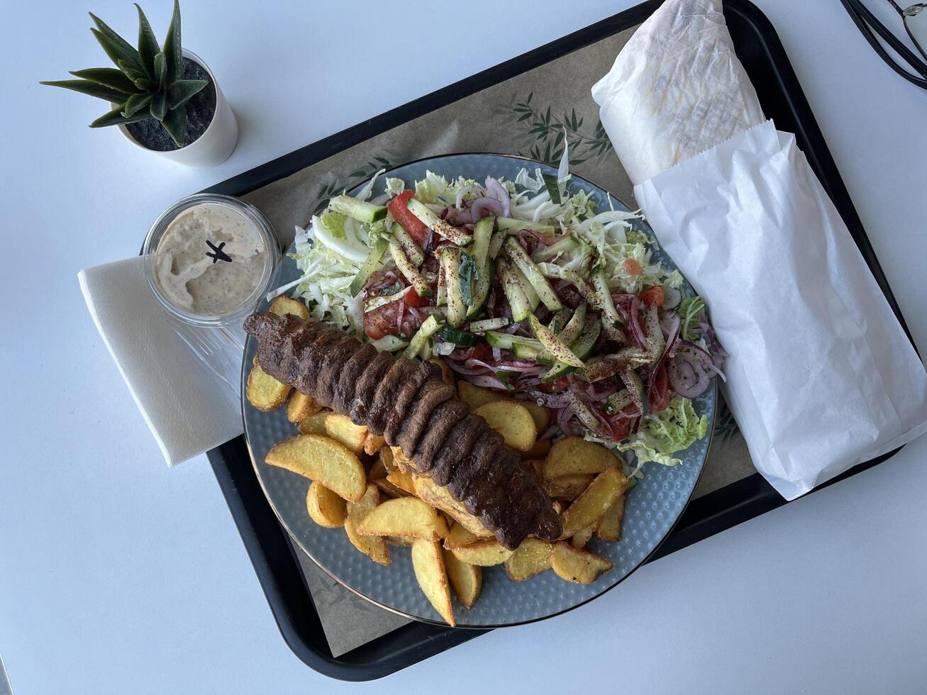 Kebab with French fries and salad on a plate in a restaurant photo