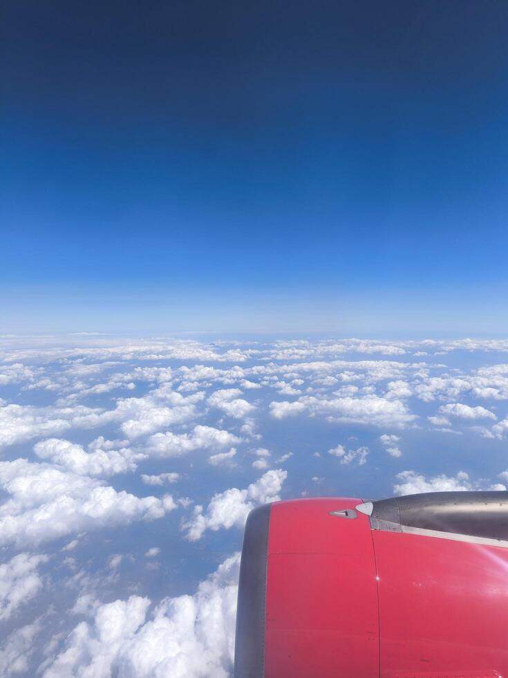 View from airplane window, wing tips, blue sky, white clouds, horizon, jet engine photo