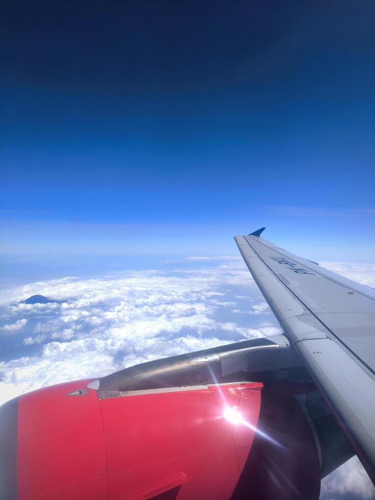 View from airplane window, wing tips, blue sky, white clouds, horizon, jet engine photo