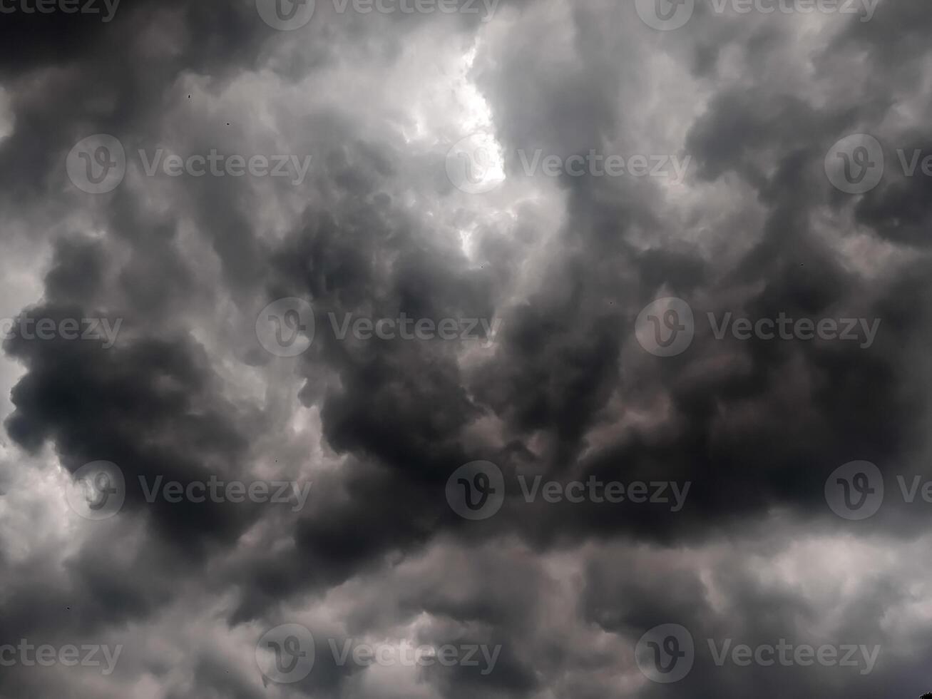 Dark, looming storm clouds dominate the sky, creating a moody, dramatic atmosphere. The overcast sky hints at an impending rainstorm, with thick clouds rolling in and covering the horizon. photo