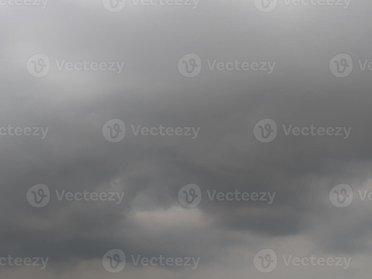 Dark, looming storm clouds dominate the sky, creating a moody, dramatic atmosphere. The overcast sky hints at an impending rainstorm, with thick clouds rolling in and covering the horizon. photo