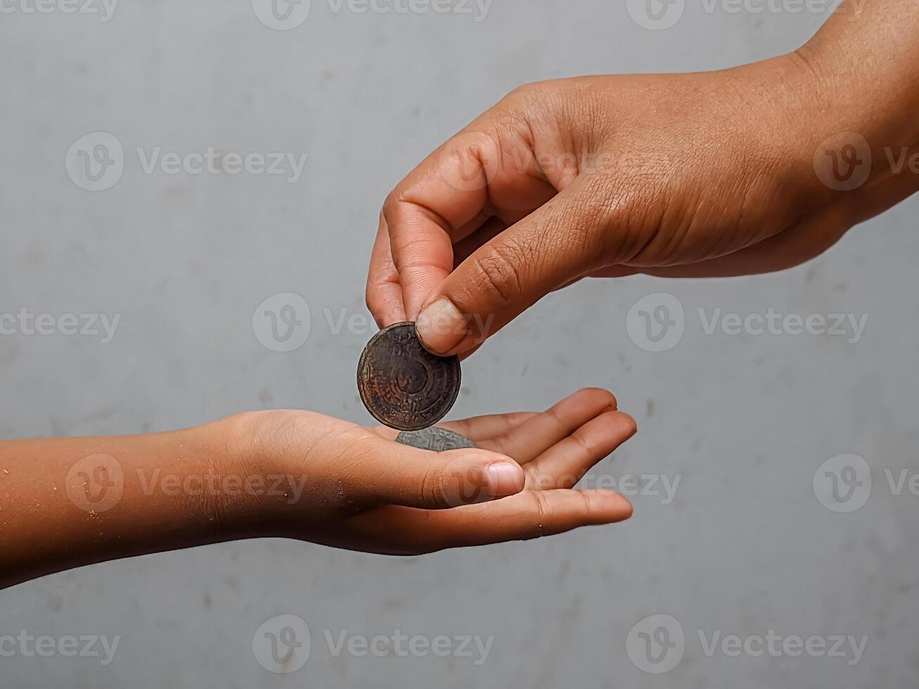 A close-up of an adult hand giving coins to a child's outstretched palm. photo