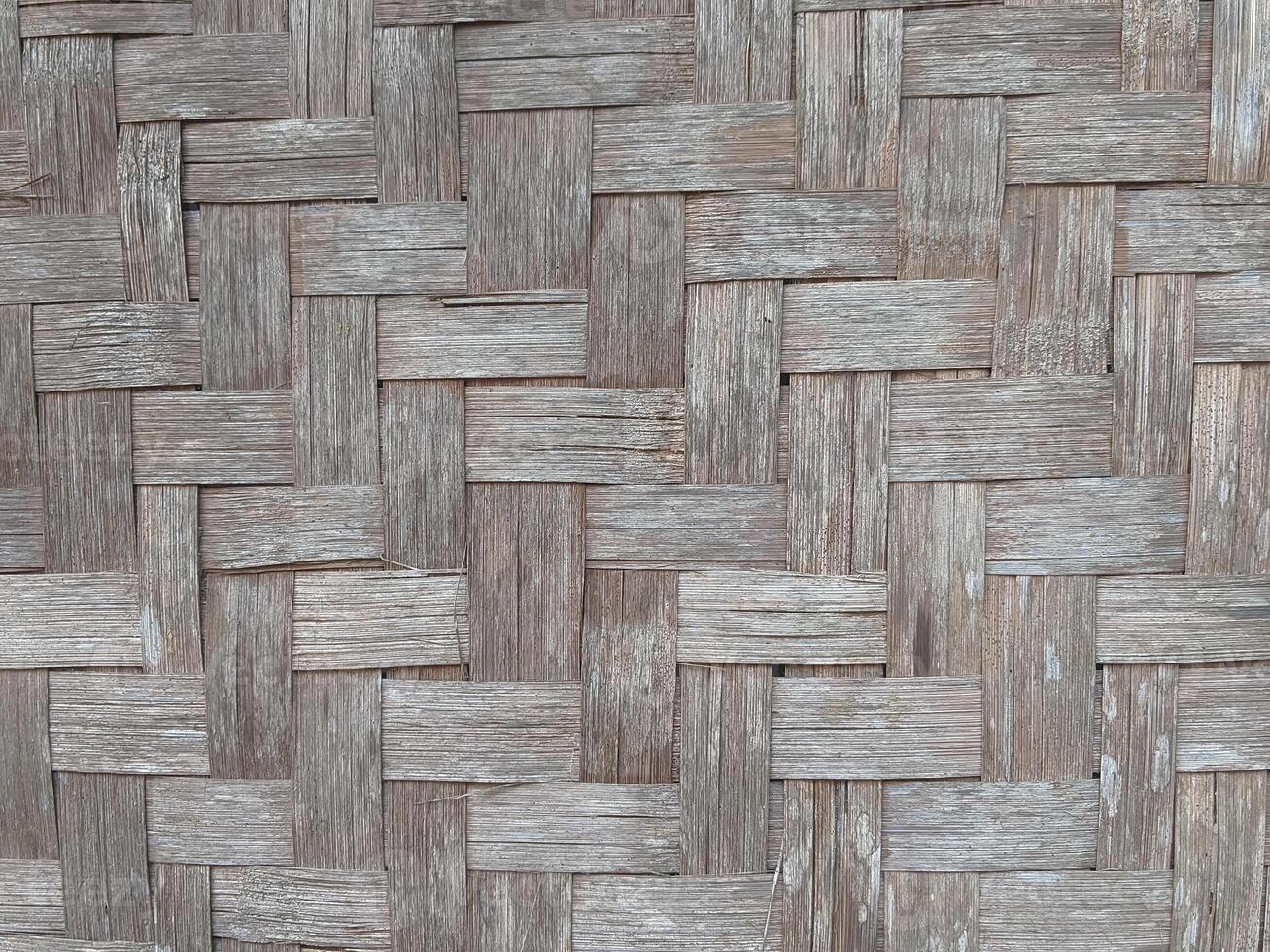 A close-up of a weathered bamboo woven wall, showcasing the intricate pattern and natural texture of the bamboo. The wall has a rustic and traditional feel. photo