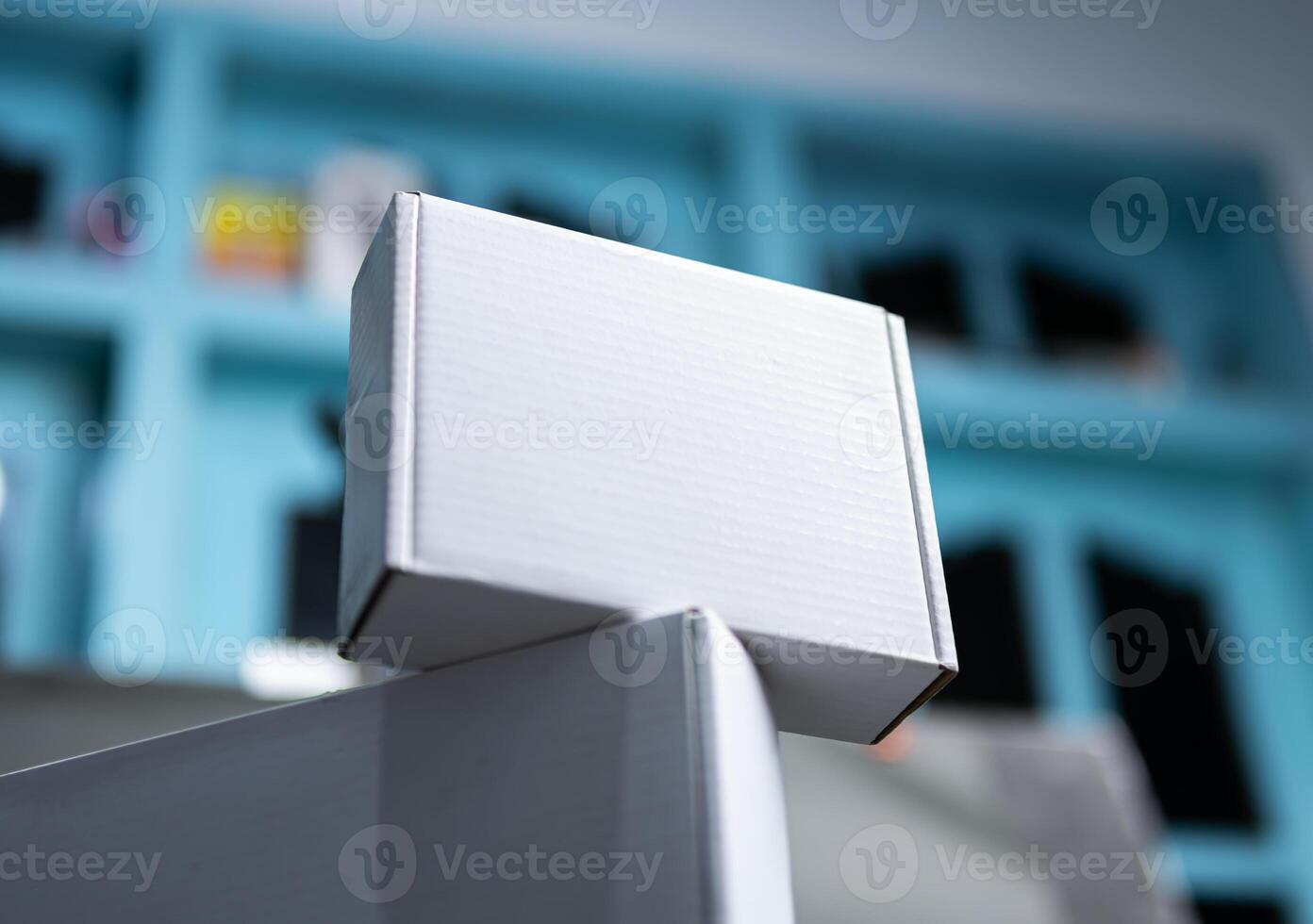 A white cardboard packaging is balanced on top of another white box photo