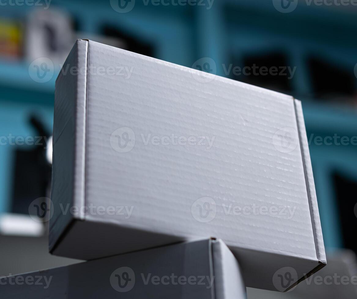 A close up of white packaging box is laying down on top of another white box photo