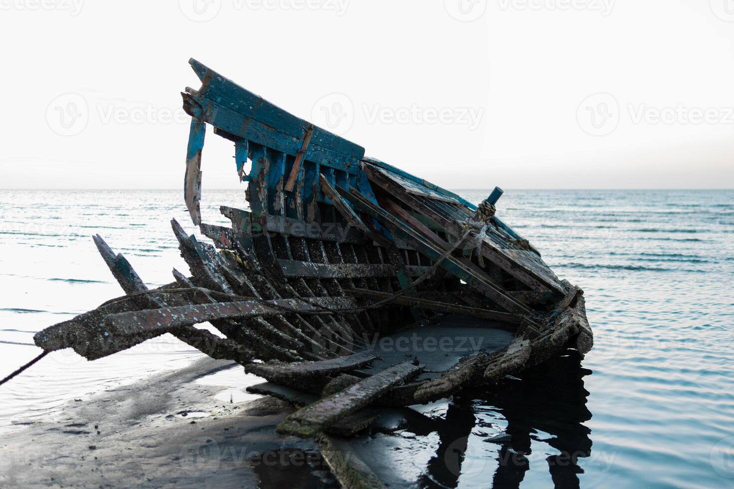 A broken boat beached on a sandy shore photo