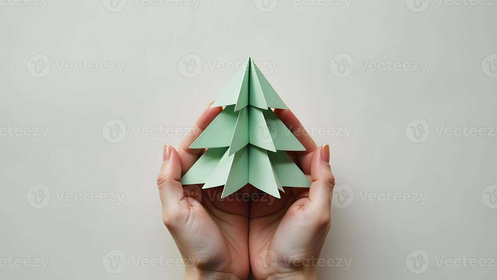 Holding a small green paper Christmas tree on a neutral background photo