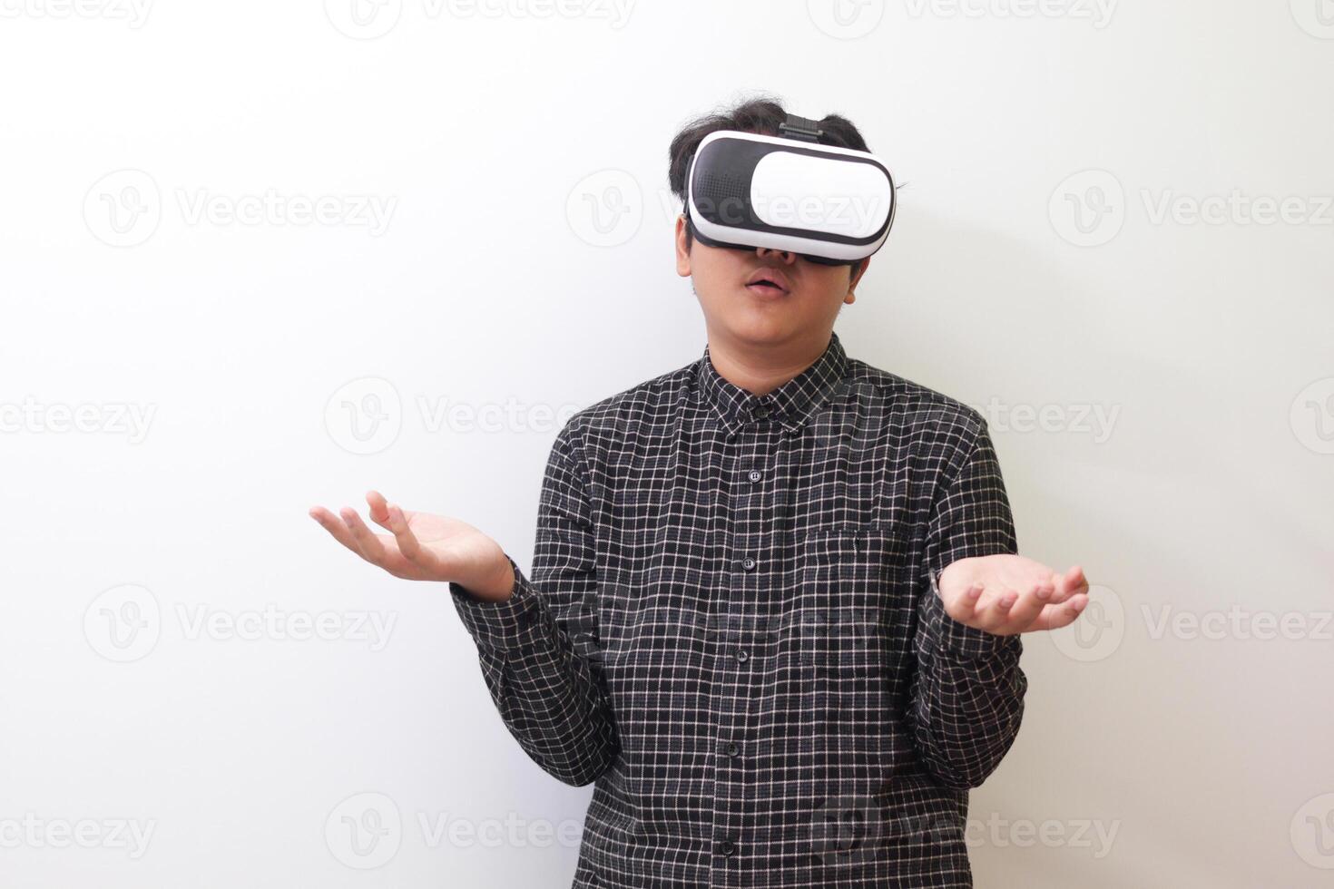 Portrait of Asian man in black plaid shirt using Virtual Reality VR glasses and protecting himself by spreading his arms from something big falling from above. Isolated image on white background photo