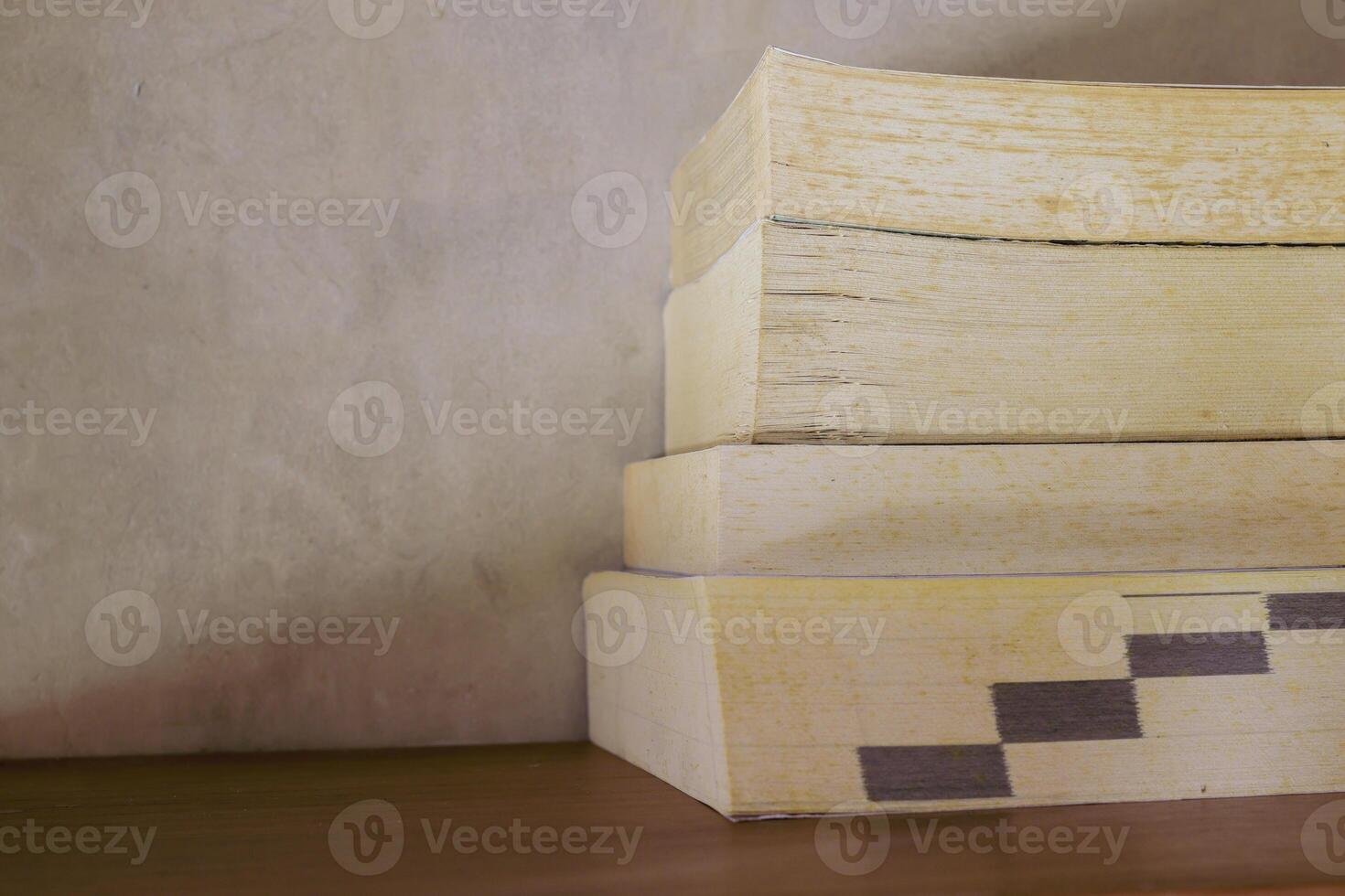 Stack of yellowish and vintage books on floating wooden bookshelf. Education and knowledge concept. Pile of books to read photo