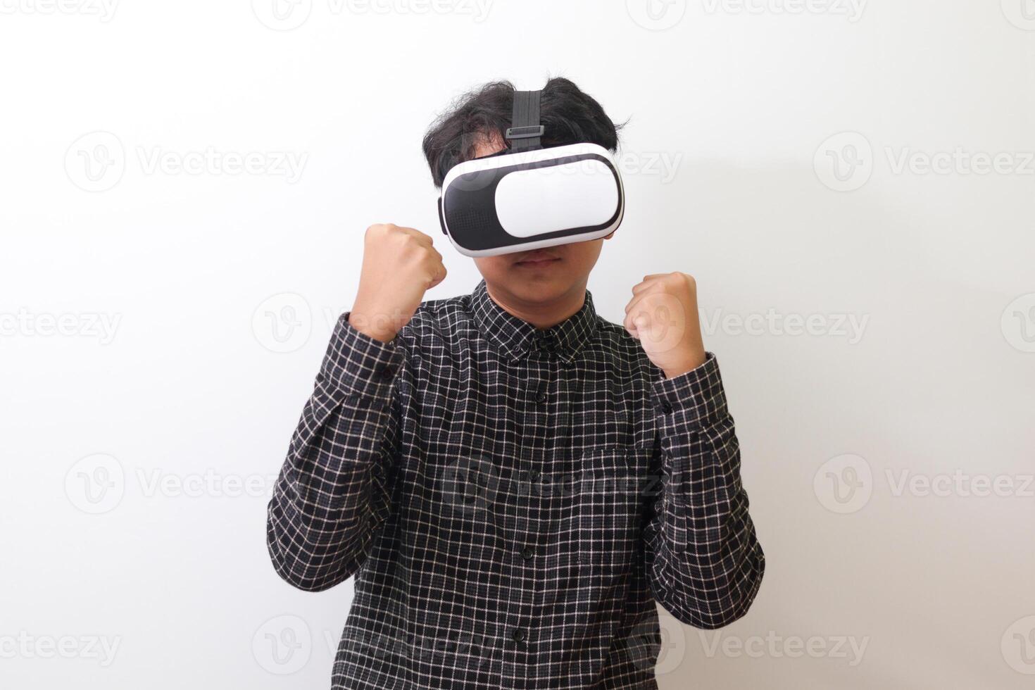 Portrait of Asian man in black plaid shirt using Virtual Reality VR glasses and trying to punch and fight something or his enemy game in front of him. Isolated image on white background photo