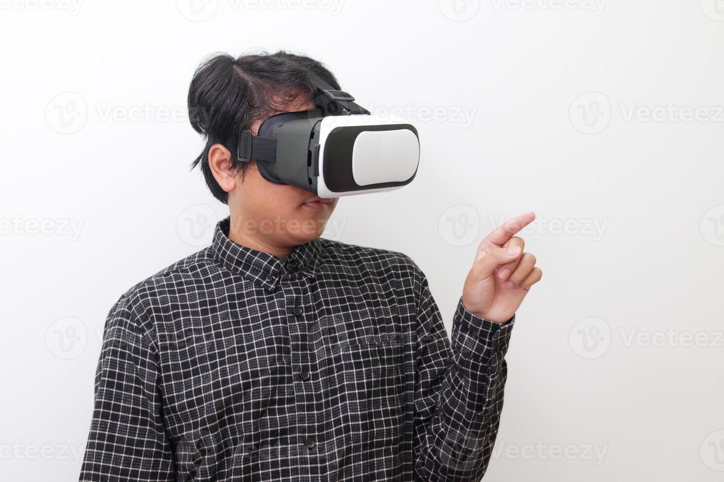 Portrait of Asian man in black plaid shirt using Virtual Reality VR glasses and trying to touch something in front of him. Isolated image on white background photo