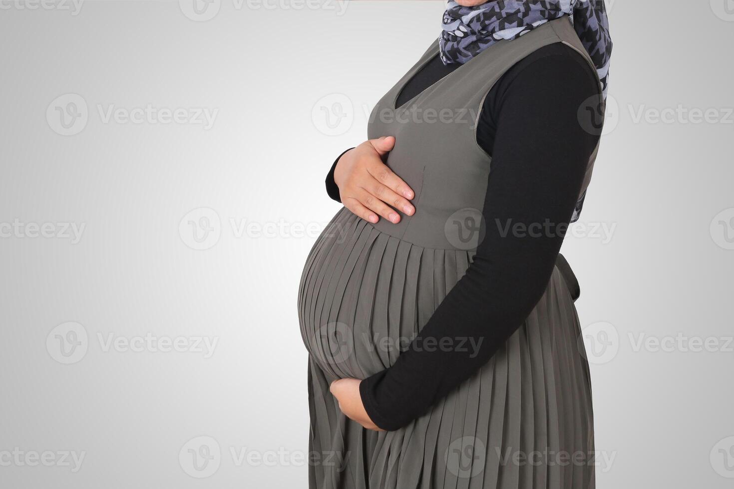 Cropped portrait of unrecognizable pregnant muslim woman with hands over tummy. Isolated image on white background photo