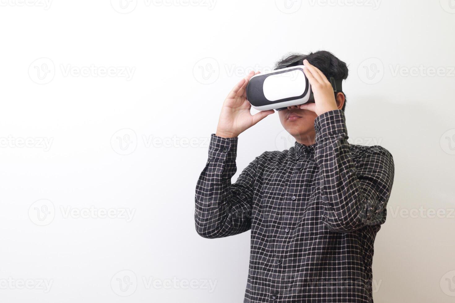 Portrait of Asian man in black plaid shirt using Virtual Reality VR glasses and looking up. Isolated image on white background photo