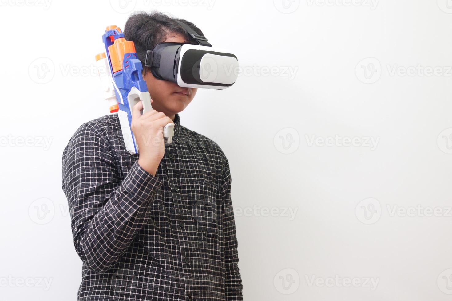 Portrait of Asian man in black plaid shirt using Virtual Reality VR glasses holding a gun weapon console. Isolated image on white background photo
