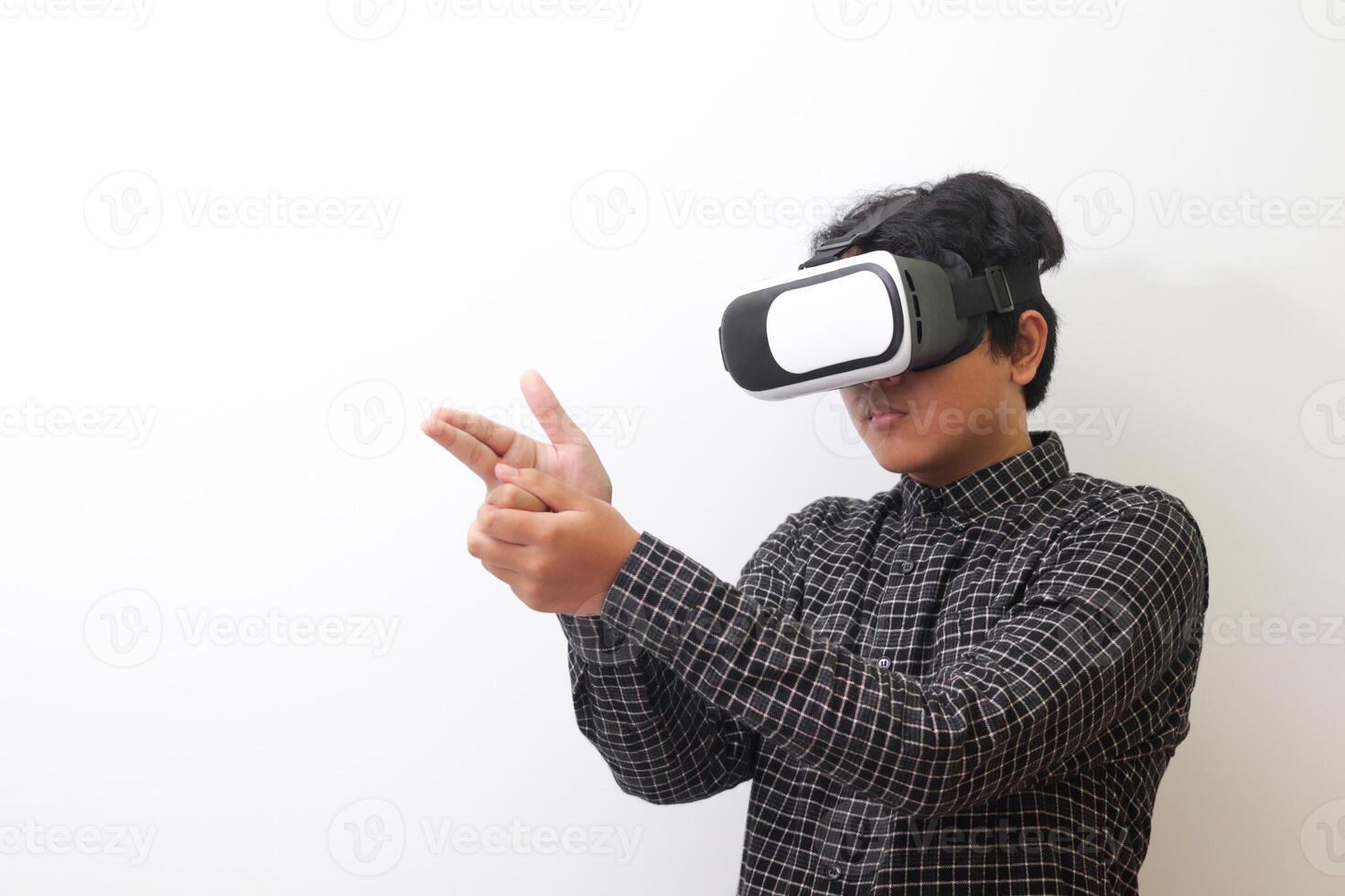 Portrait of Asian man in black plaid shirt using Virtual Reality VR glasses and greet his friend inside the game with opened palm. Isolated image on white background photo