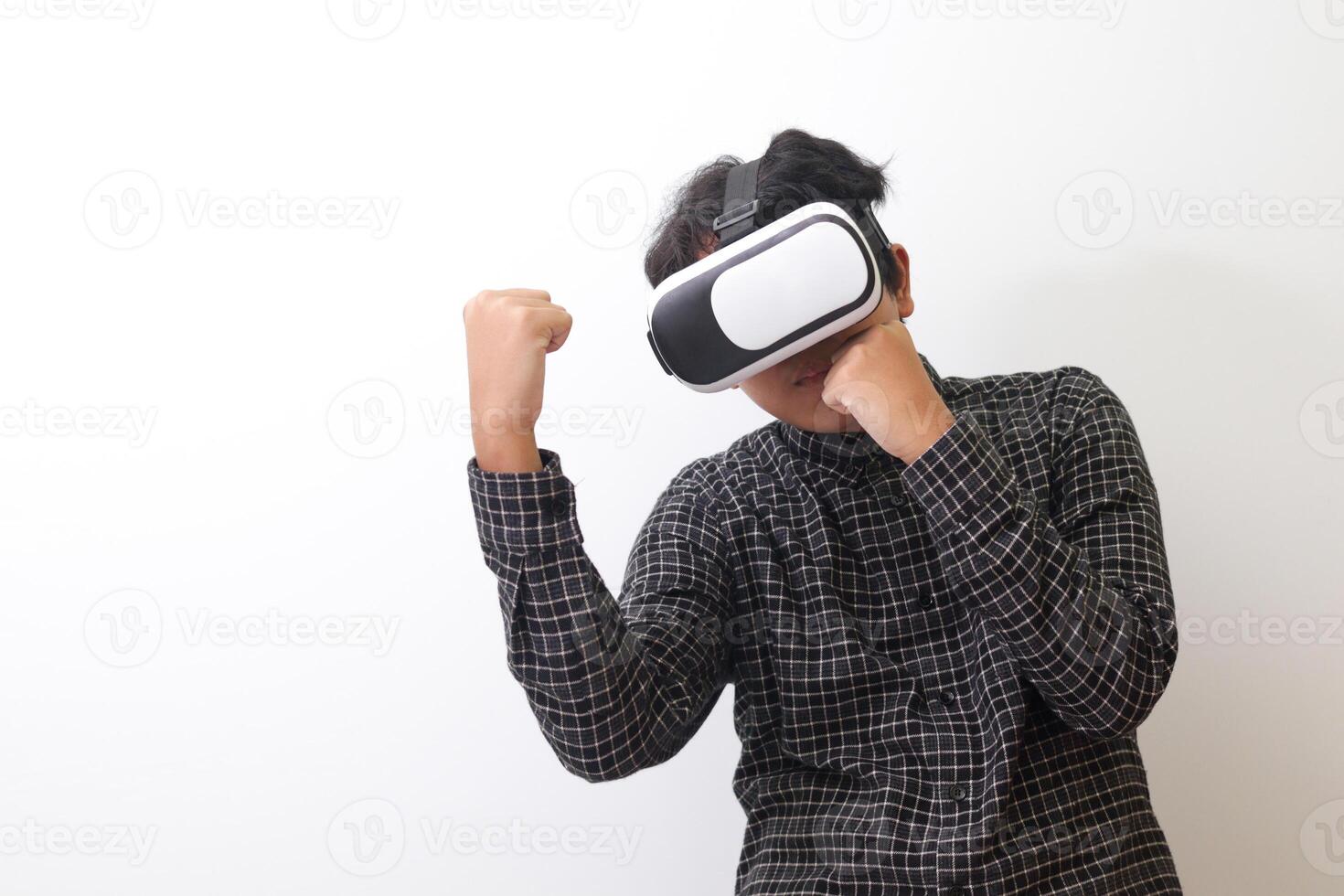 Portrait of Asian man in black plaid shirt using Virtual Reality VR glasses and trying to punch and fight something or his enemy game in front of him. Isolated image on white background photo